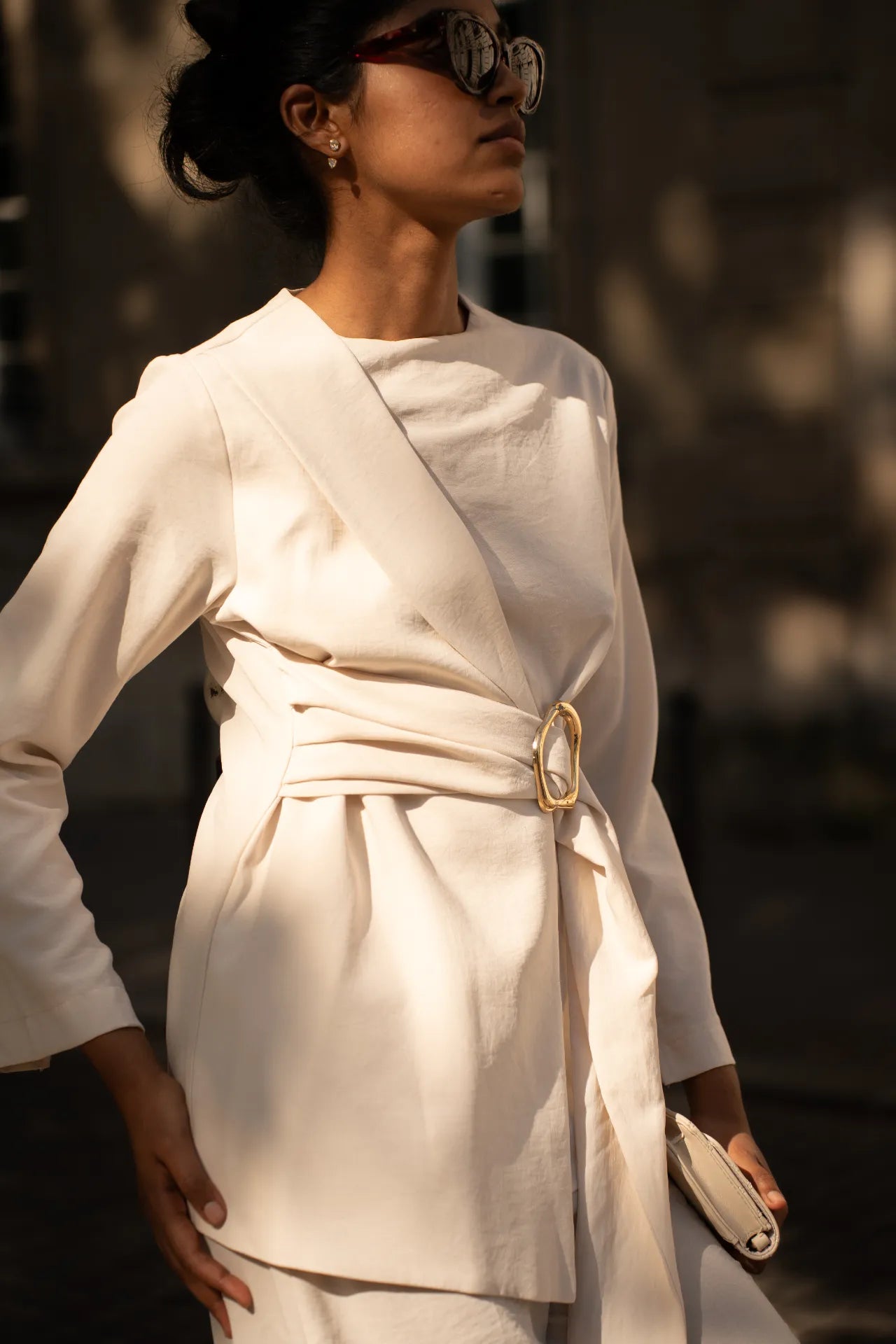 Gros plan sur une veste blanche élégante avec ceinture à boucle dorée