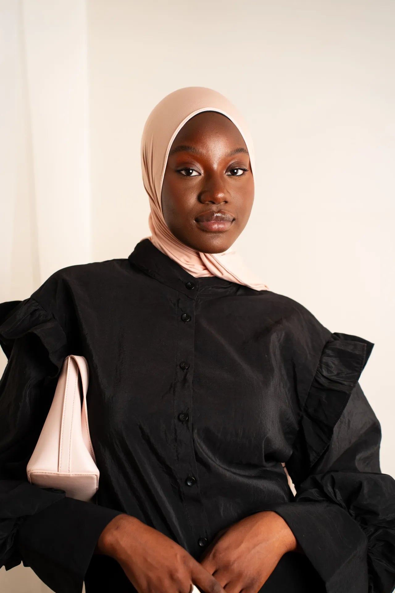 Robe-chemise noire à volants portée avec hijab et sac rose