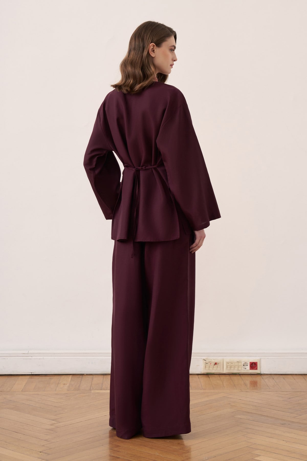 Vue de dos d'un ensemble tunique longue ceinturée et pantalon amples violet prune