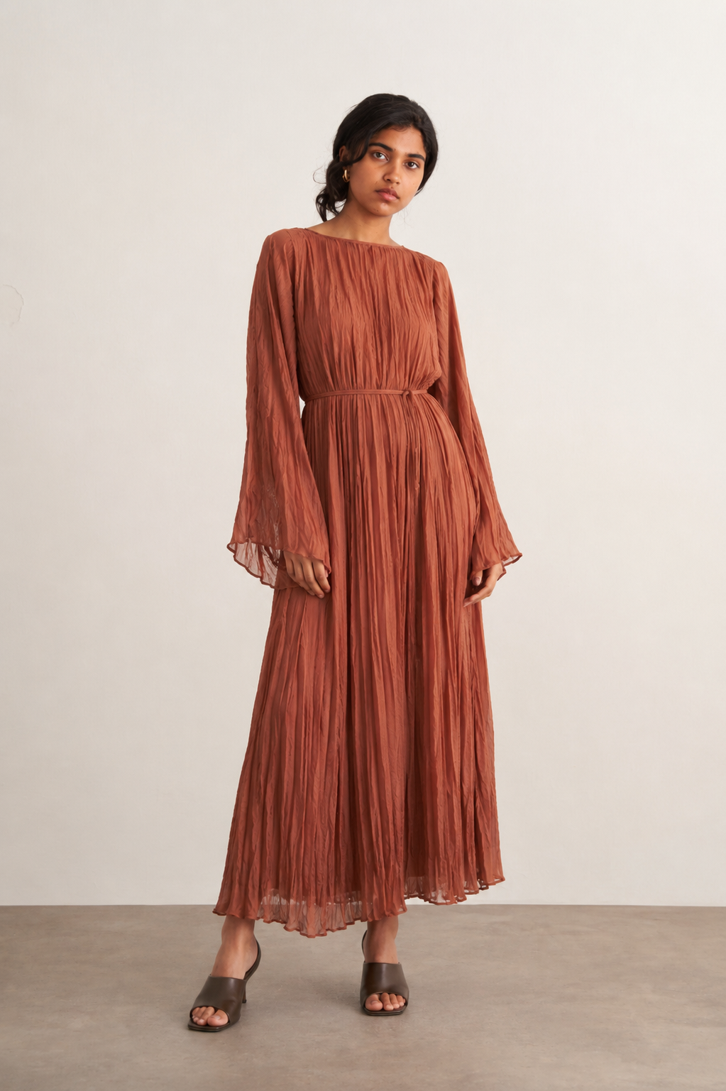 Vue de face d'une robe longue plissée terracotta à manches évasées