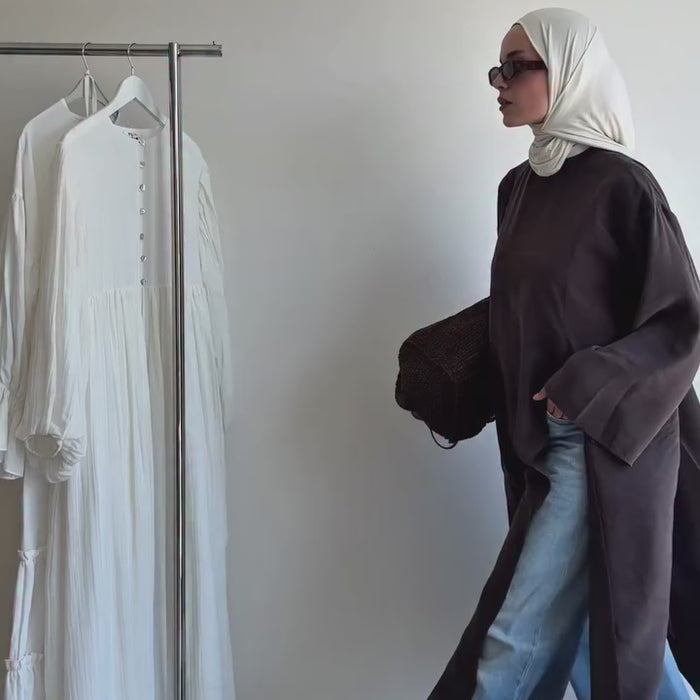 Vidéo montrant une tunique longue ample marron foncé portée avec un jean et un hijab blanc