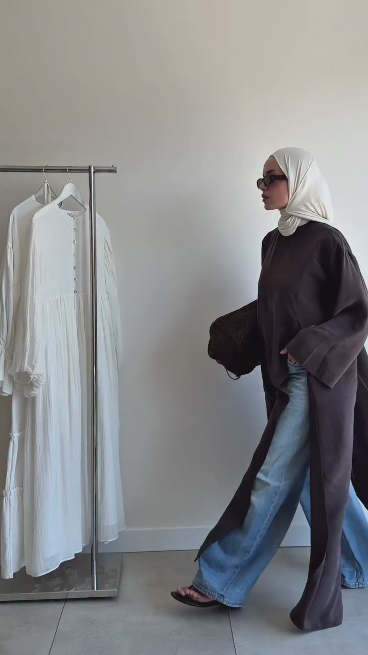 Vidéo montrant une tunique longue ample marron foncé portée avec un jean et un hijab blanc
