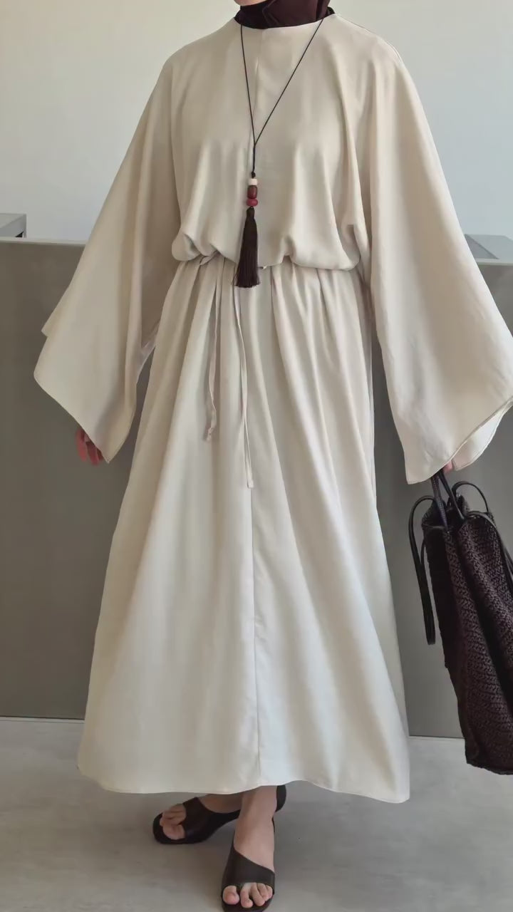 Vidéo montrant une robe longue ceinturée blanc cassé avec hijab noir